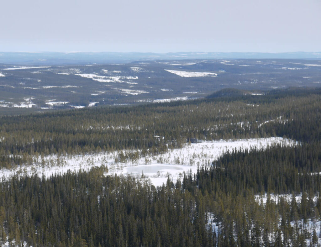 Blick vom Rand des Hochplateaus des Fulufjells nach Nordosten hinab am 27.03.2014. Am hinteren Rand des Moores im Bildzentrum ist am Rand des Bergwaldes das Naturpark-Informationszentrum "Naturum" erkennbar.