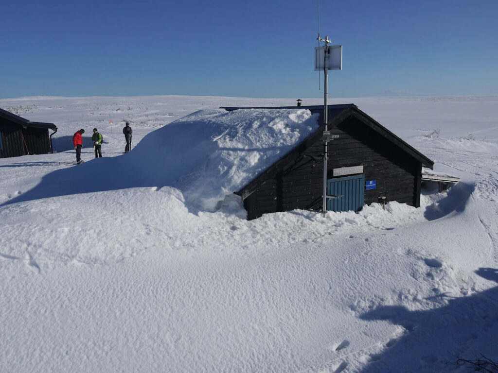 Die Rasthütte der kleinen Hüttensiedlung Rörsjöstugorna auf dem Hochplateau des Fulufjells im Tiefschnee am 10.03.2014. Zu einer regulären Schutzhüttenausstattung gehört neben Säge und Axt auch eine Schneeschaufel, die normalerweise über der Eingangstür unter dem Dachgiebel angebracht ist, damit der Zugang zur Schutzhütte im Winter auch bei mehreren Metern Teifschnee ausgegraben werden kann.